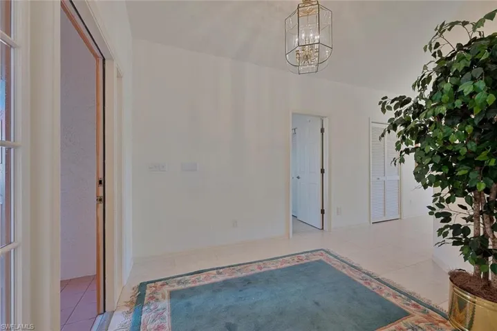 Foyer entrance with light tile patterned flooring and an inviting chandelier