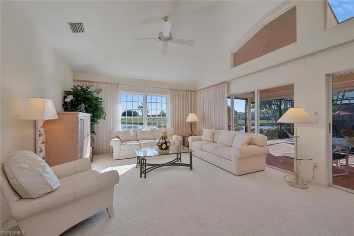 Living room featuring ceiling fan, carpet flooring, and high vaulted ceiling, and water and golf course views