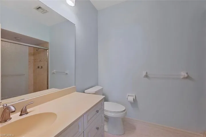 2nd Bathroom with tile patterned flooring, vanity, a shower with shower door, and toilet