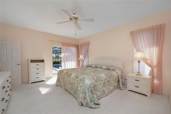 Carpeted bedroom with ceiling fan and access to outside pool area