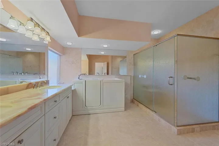 Bathroom featuring vanity, jacuzzi tub and a shower with shower door
