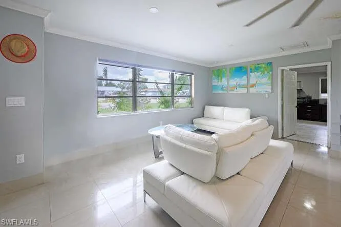 Living room featuring ceiling fan, light tile patterned floors, and ornamental molding