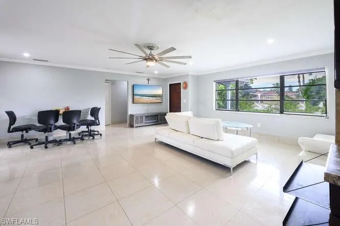 Tiled living room with ornamental molding and ceiling fan