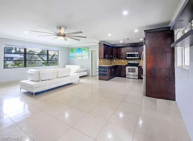 Unfurnished living room featuring crown molding, ceiling fan, and light tile patterned floors