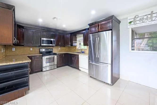 Kitchen with backsplash, appliances with stainless steel finishes, a wealth of natural light, and ornamental molding