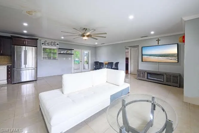Living room featuring french doors, ceiling fan, ornamental molding, and light tile patterned floors