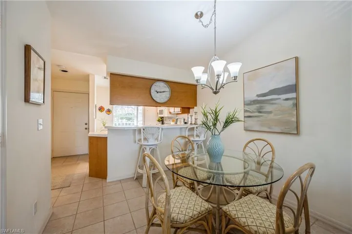 Dining space with light tile patterned flooring and a chandelier