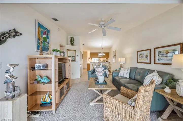 Living area featuring a ceiling fan, a chandelier, and tile patterned flooring