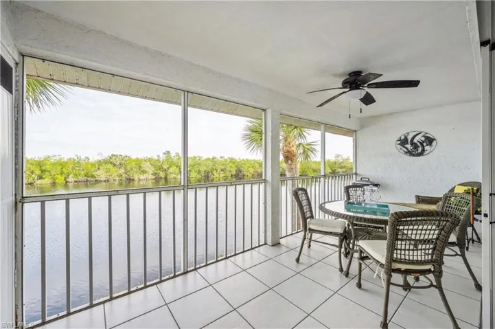Sunroom / solarium with a water view, ceiling fan, outdoor dining space, and view of scattered trees