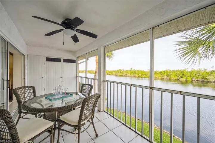 Sunroom featuring a water view, tile patterned floors, ceiling fan, and a balcony