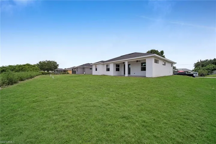 Rear view of house with a lawn, a ceiling fan, stucco siding, and a patio area