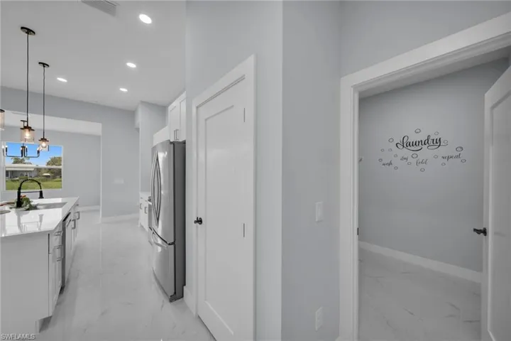 Kitchen featuring white cabinetry, light marble finish flooring, freestanding refrigerator, hanging light fixtures, and recessed lighting