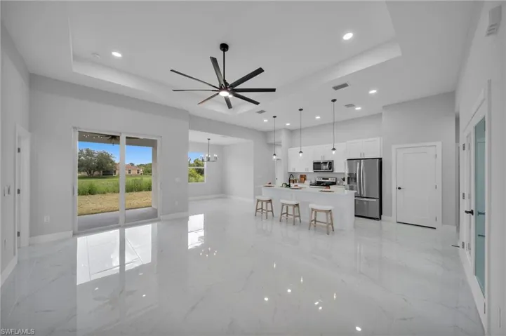 Kitchen featuring a raised ceiling, white cabinets, open floor plan, stainless steel appliances, and recessed lighting