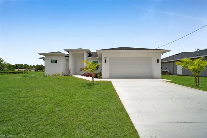 Prairie-style house with concrete driveway, a front lawn, stucco siding, and a garage