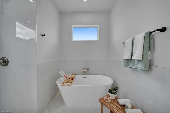 Full bath with a freestanding tub and marble finish flooring