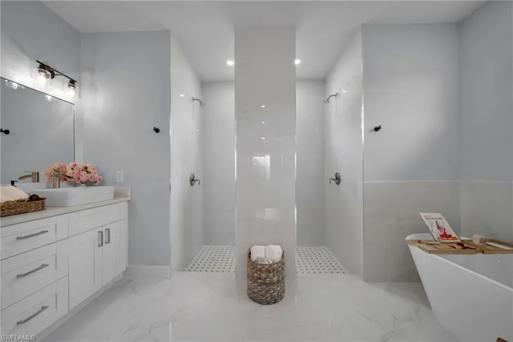 Bathroom featuring a soaking tub, a marble finish shower, vanity, recessed lighting, and light marble finish flooring