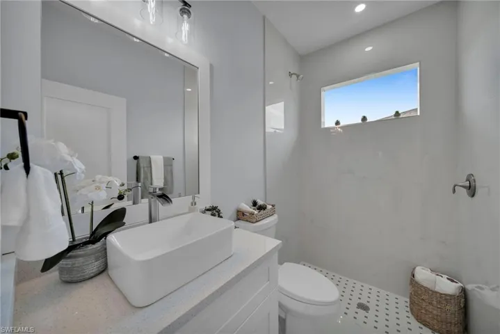 Full bathroom featuring vanity, a marble finish shower, and recessed lighting