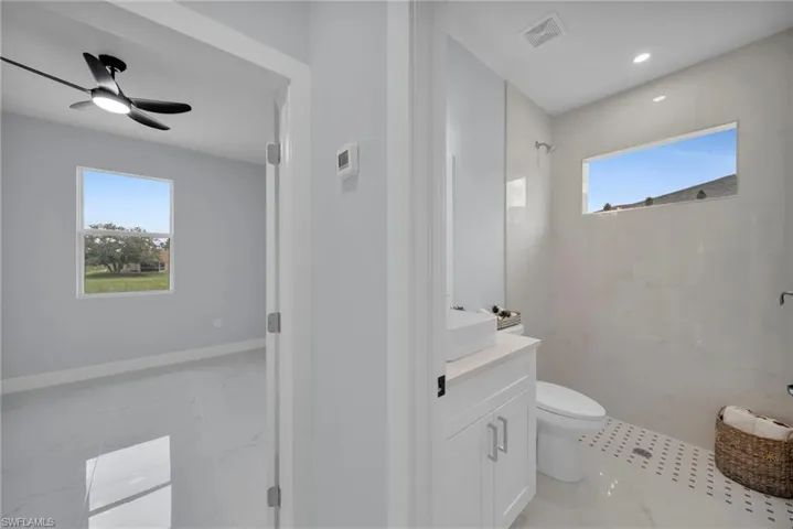 Full bathroom with vanity, a marble finish shower, and a ceiling fan
