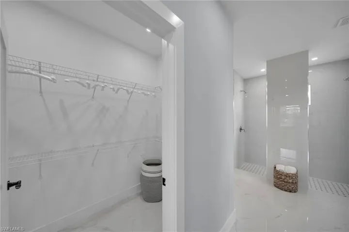Bathroom featuring a walk in closet, a marble finish shower, light marble finish floors, and recessed lighting