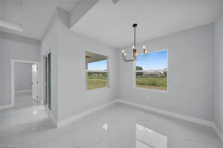 Unfurnished dining area featuring light marble finish floors and a chandelier