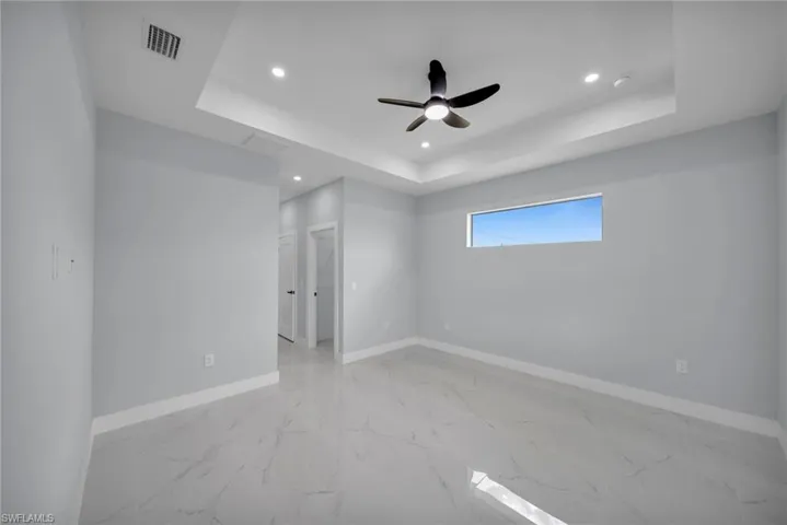 Unfurnished room with light marble finish flooring, a raised ceiling, recessed lighting, and a ceiling fan