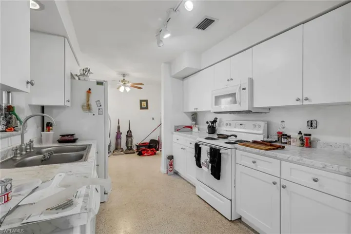 Kitchen featuring white appliances, light countertops, white cabinetry, a ceiling fan, and track lighting