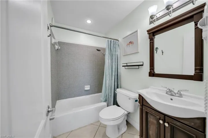 Bathroom featuring vanity, shower / bathtub combination with curtain, light tile patterned flooring, and recessed lighting