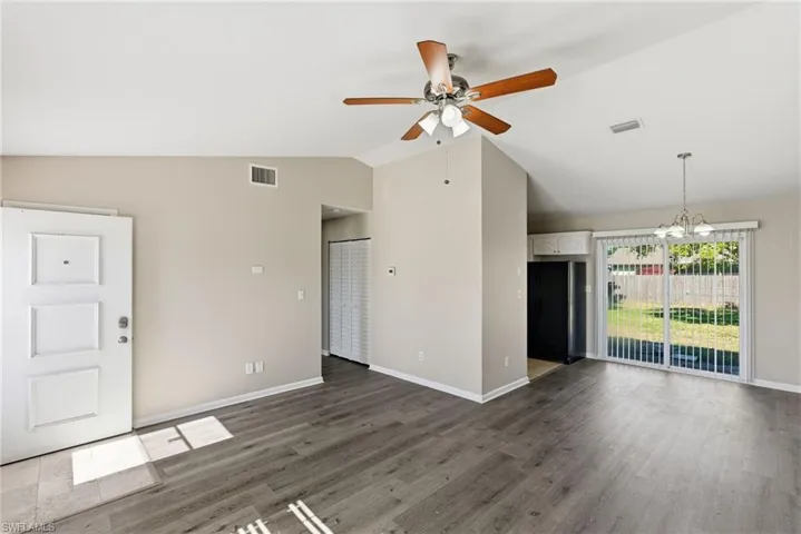Unfurnished living room with a ceiling fan, vaulted ceiling, a chandelier, and wood finished floors
