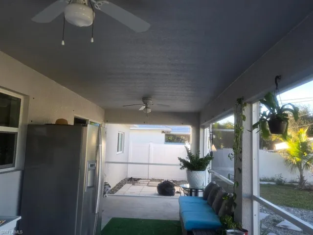 Fenced backyard featuring ceiling fan and a sunroom