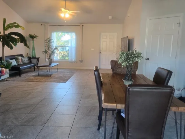 Dining area featuring a ceiling fan, vaulted ceiling, and tile patterned floors
