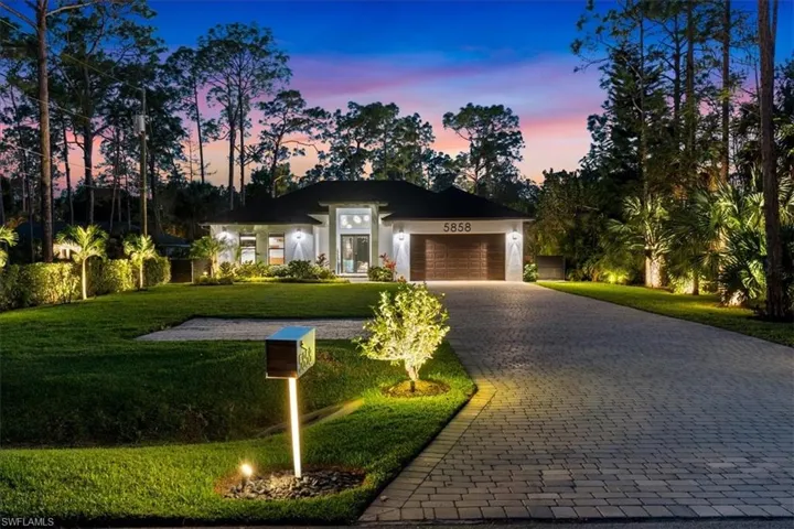 View of front of home featuring a garage, a front yard, stucco siding, and decorative driveway