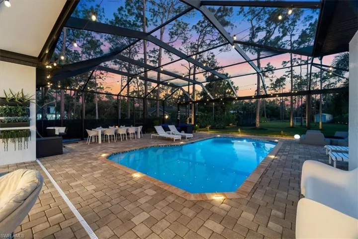 Pool at dusk with an outdoor pool, a patio, and a lanai
