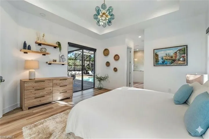 Bedroom with a raised ceiling, light wood finished floors, access to outside, and recessed lighting