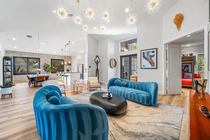 Living room with light wood finished floors, a towering ceiling, visible vents, and plenty of natural light