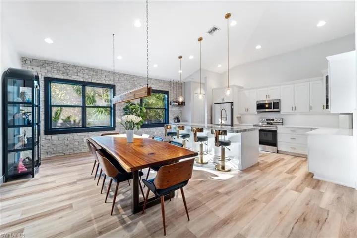 Dining space with recessed lighting, light wood finished floors, visible vents, and a high ceiling