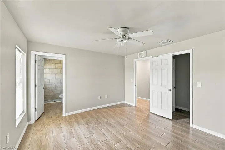 Wood-finish flooring, ceiling fan, neutral wall tones, interior panel doors, and window with blinds