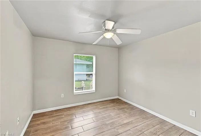 Wood-finish plank flooring, neutral wall tones, and a ceiling fan with integrated lighting