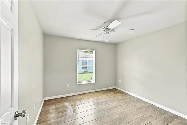 Wood-finish tile flooring, ceiling fan, and window with blinds