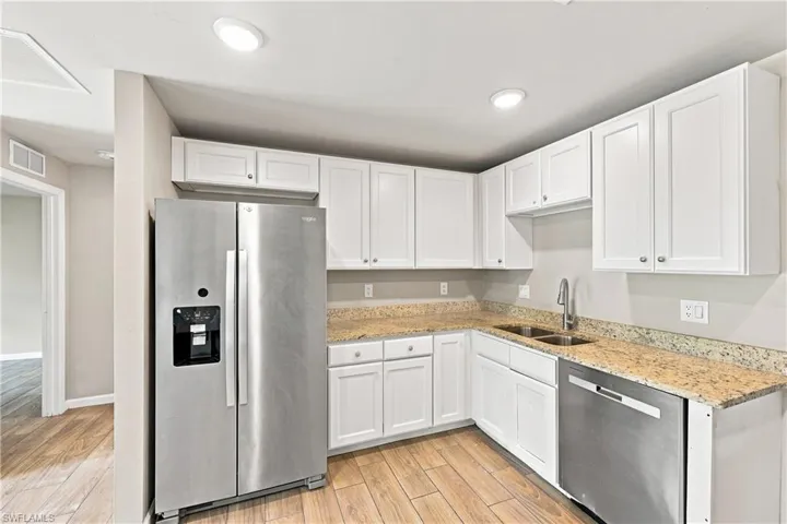 Kitchen featuring white cabinetry, light-toned countertops, stainless steel appliances, and recessed lighting