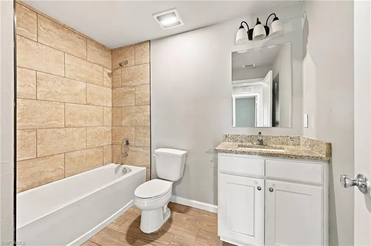Bathroom featuring a white vanity with a light-colored countertop, an undermount sink, a large mirror, and a three-light fixture