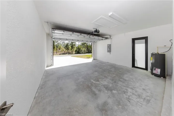 Garage featuring electric water heater, a textured wall, and electric panel