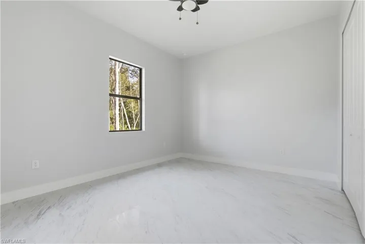 Empty room featuring light marble finish flooring and a ceiling fan