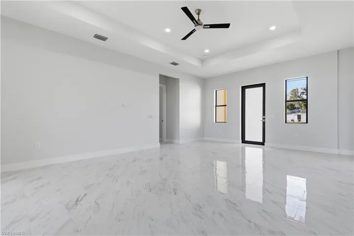 Spare room with a tray ceiling, a ceiling fan, recessed lighting, and light marble finish floors