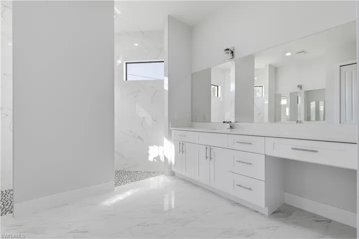 Bathroom with light marble finish floors, vanity, and a marble finish shower