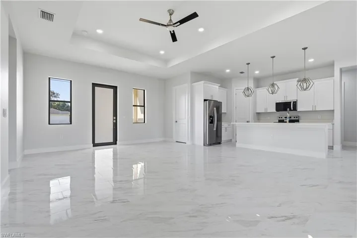 Unfurnished living room with light marble finish floors, recessed lighting, ceiling fan, and a raised ceiling