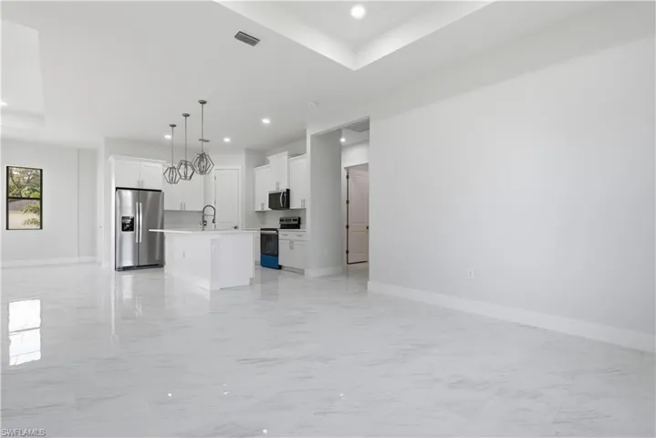 Unfurnished living room featuring light marble finish floors, recessed lighting, and a chandelier