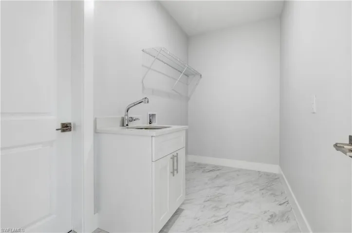 Washroom with light marble finish flooring, hookup for a washing machine, and cabinet space