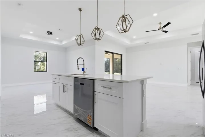 Kitchen featuring a tray ceiling, open floor plan, light marble finish flooring, healthy amount of natural light, and recessed lighting