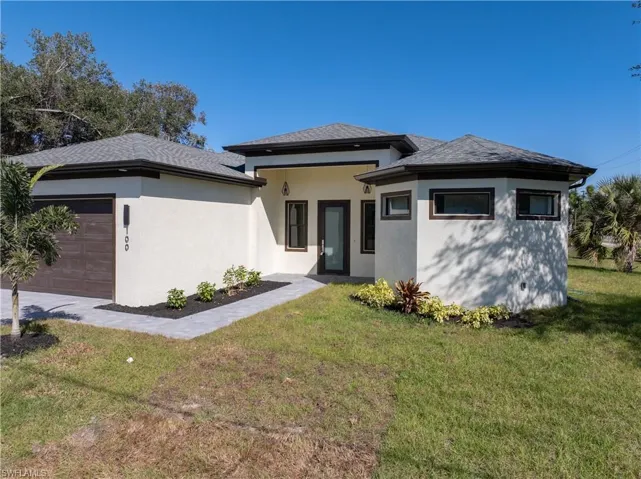 Prairie-style home with stucco siding, a front lawn, and a garage