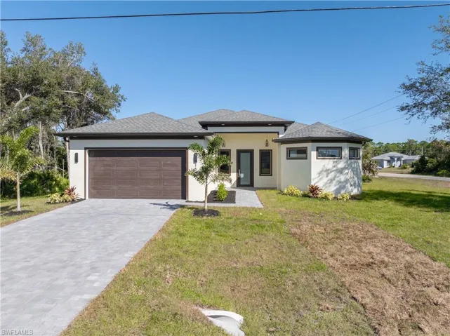 Prairie-style house featuring stucco siding, a front lawn, and decorative driveway